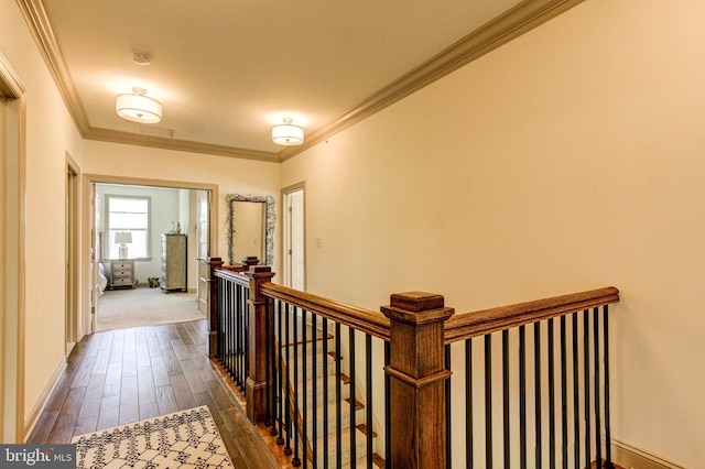 hallway with an upstairs landing, dark wood-style floors, ornamental molding, and baseboards