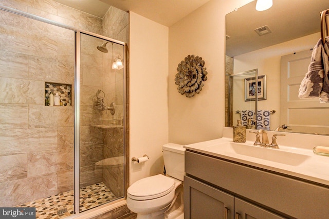 bathroom featuring a shower stall, toilet, and vanity