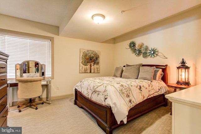 bedroom with light colored carpet, baseboards, and a desk