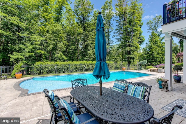 view of swimming pool featuring a patio area, outdoor dining area, and view of scattered trees