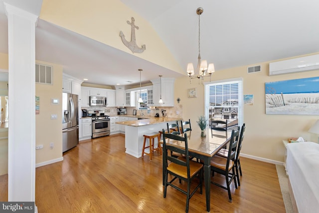 127 E 13th St, Long Beach Township, NJ 08008 - dining room with a wall mounted AC, a chandelier, vaulted ceiling, light wood-style floors, and baseboards