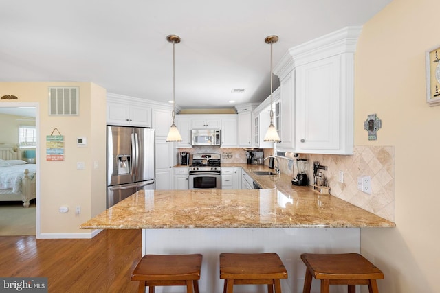 127 E 13th St, Long Beach Township, NJ 08008 - kitchen with stainless steel appliances, a peninsula, white cabinetry, and light stone counters