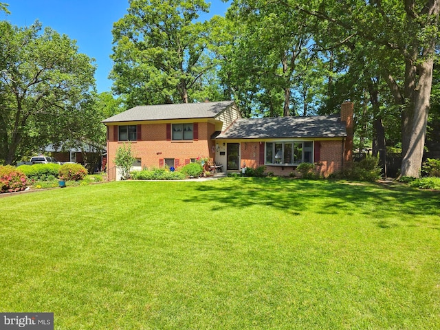 tri-level home featuring a front yard, brick siding, and a chimney
