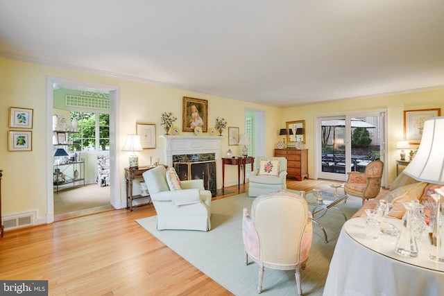 living room with wood finished floors, a high end fireplace, ornamental molding, and baseboards
