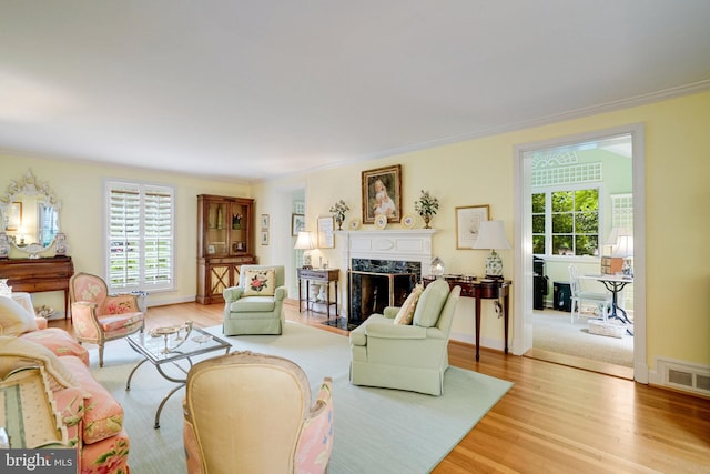 living room with a fireplace, ornamental molding, and light wood-style floors