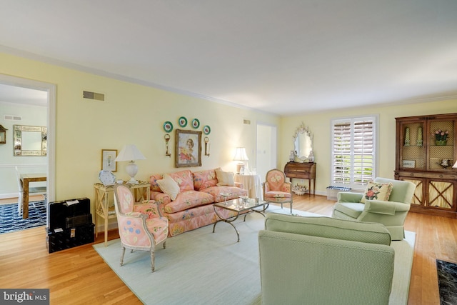living room featuring light wood-style floors and crown molding