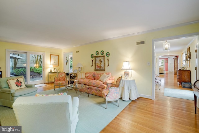 living area with arched walkways, light wood-type flooring, crown molding, and baseboards