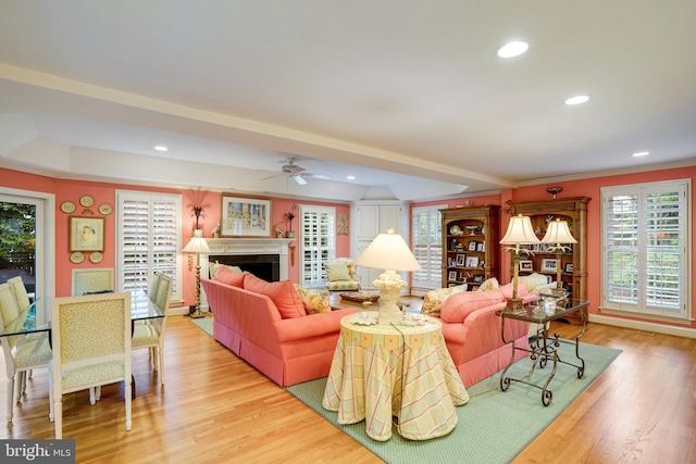 living room with ornamental molding, light wood-style flooring, a ceiling fan, recessed lighting, and a fireplace