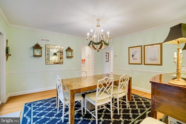 dining room featuring light wood-style floors, a chandelier, crown molding, and baseboards