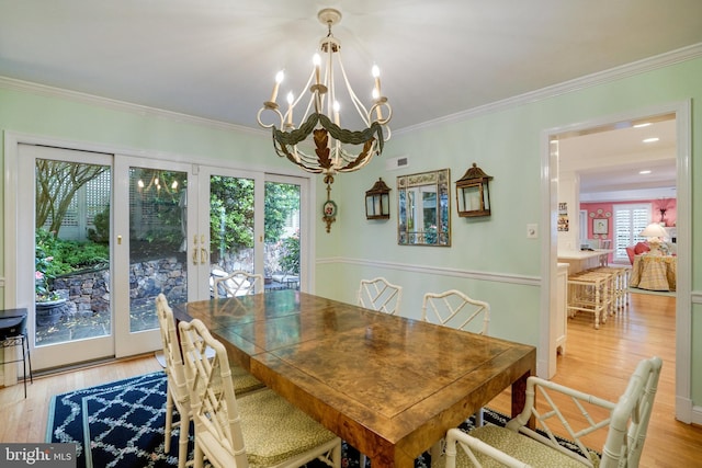 dining room with french doors, a chandelier, crown molding, and light wood finished floors