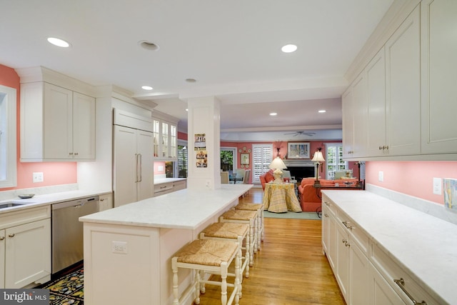 kitchen featuring dishwasher, a breakfast bar area, a ceiling fan, recessed lighting, and light wood-style flooring