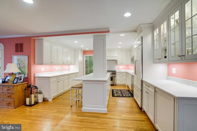 kitchen with stainless steel appliances, a breakfast bar area, a kitchen island, light wood-style flooring, and white cabinets