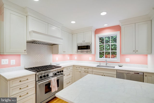 kitchen featuring appliances with stainless steel finishes, a sink, light stone counters, and recessed lighting