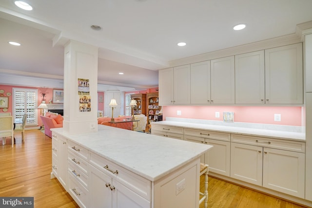 kitchen with light wood-type flooring, a breakfast bar, recessed lighting, open floor plan, and white cabinetry