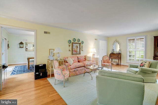 living area featuring light wood-style flooring and ornamental molding