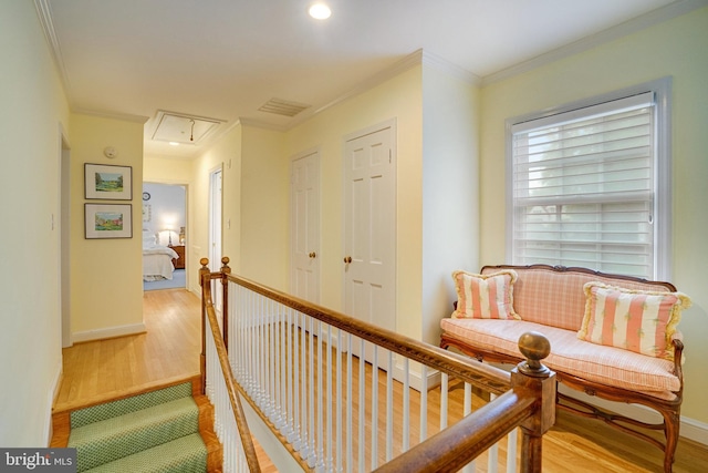 corridor with attic access, wood finished floors, ornamental molding, baseboards, and recessed lighting