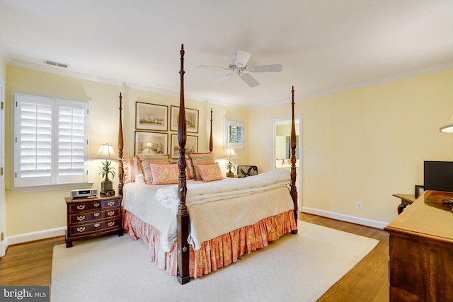 bedroom featuring wood finished floors, ornamental molding, baseboards, multiple windows, and ceiling fan