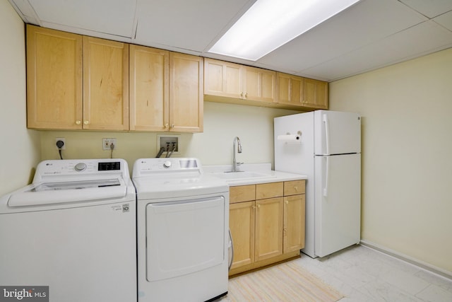 washroom featuring light marble finish floors, washing machine and dryer, cabinet space, and baseboards