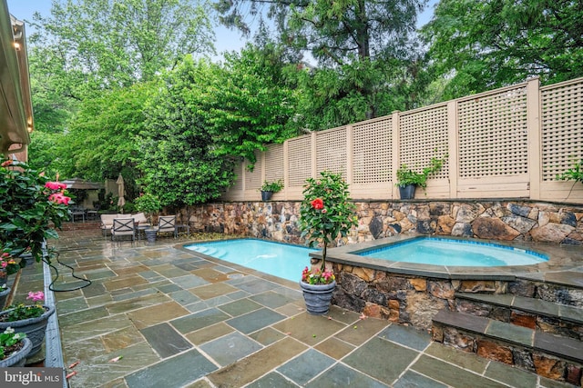 view of pool featuring a patio, an in-ground hot tub, and a fenced backyard