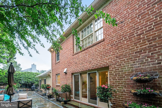 view of property exterior with a patio and brick siding