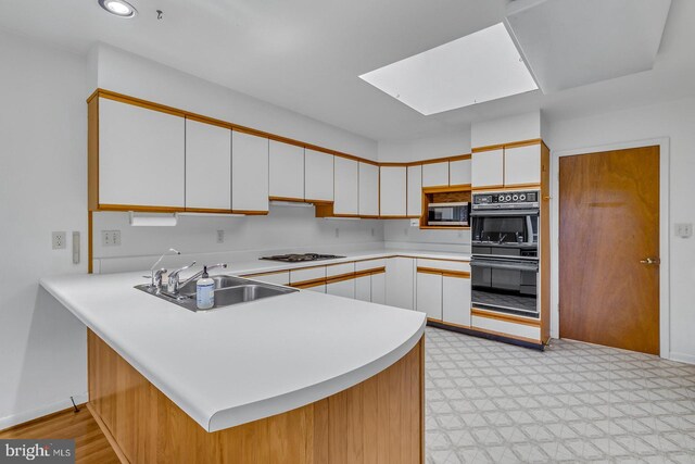 109 Kingfisher Cir, Weems, VA 22576 - kitchen featuring stainless steel microwave, a sink, a skylight, light countertops, and a peninsula