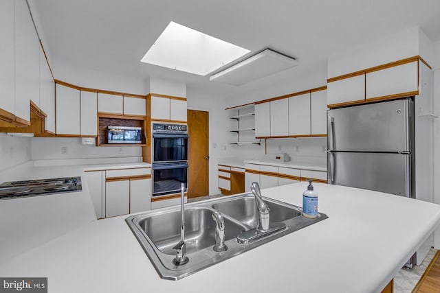 109 Kingfisher Cir, Weems, VA 22576 - kitchen featuring stainless steel appliances, a skylight, open shelves, a sink, and white cabinetry