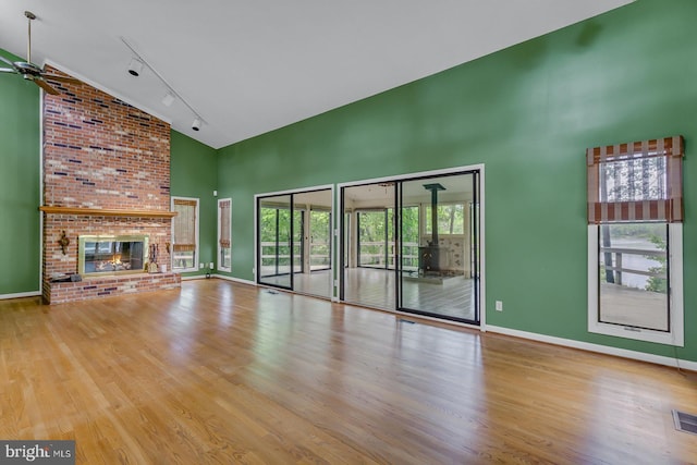 109 Kingfisher Cir, Weems, VA 22576 - unfurnished living room with high vaulted ceiling, rail lighting, wood finished floors, baseboards, and a fireplace