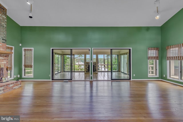 109 Kingfisher Cir, Weems, VA 22576 - unfurnished living room with rail lighting, a high ceiling, wood finished floors, baseboards, and french doors