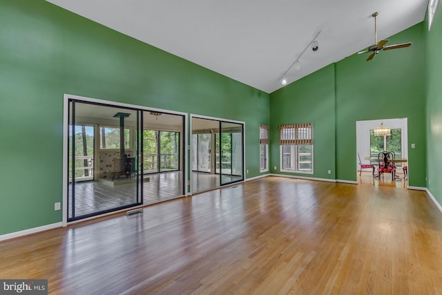 109 Kingfisher Cir, Weems, VA 22576 - empty room featuring a high ceiling, a wood stove, ceiling fan, and plenty of natural light
