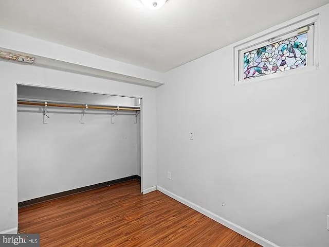 unfurnished bedroom with a closet, wood finished floors, and baseboards