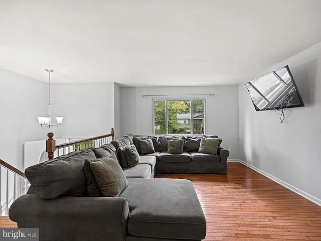 living area featuring a chandelier, wood finished floors, and baseboards