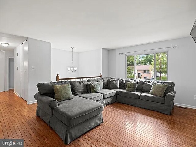 living area featuring a chandelier, hardwood / wood-style floors, and baseboards