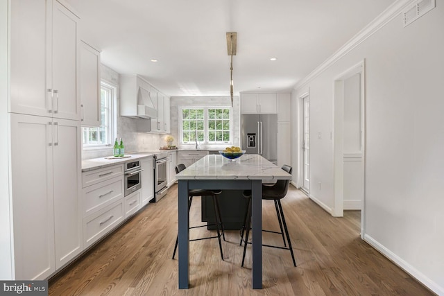 4701 Fort Sumner Dr, Bethesda, MD 20816 - kitchen featuring appliances with stainless steel finishes, white cabinetry, a breakfast bar area, light stone countertops, and a sink