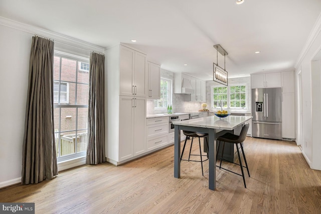 4701 Fort Sumner Dr, Bethesda, MD 20816 - kitchen featuring stainless steel appliances, crown molding, a breakfast bar, white cabinetry, and light wood finished floors