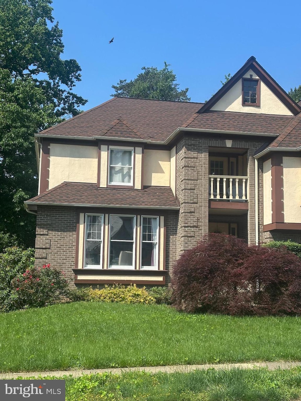 view of side of property with a yard, brick siding, roof with shingles, and stucco siding