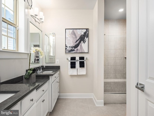 full bathroom featuring baseboards, tile patterned flooring, double vanity, a walk in shower, and recessed lighting
