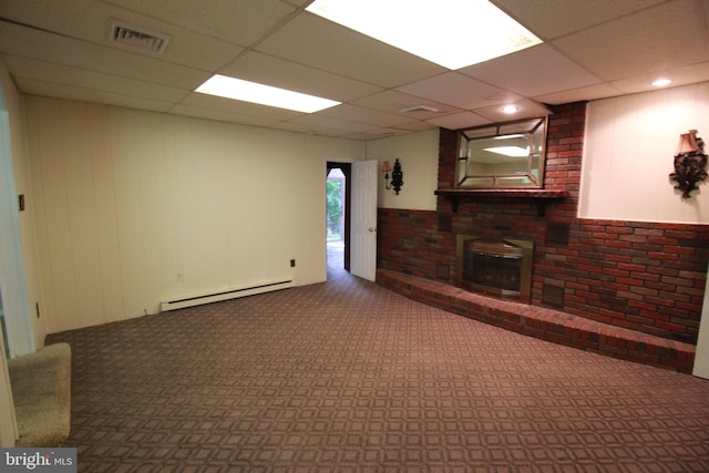 unfurnished living room with a baseboard radiator, a brick fireplace, carpet flooring, and a drop ceiling