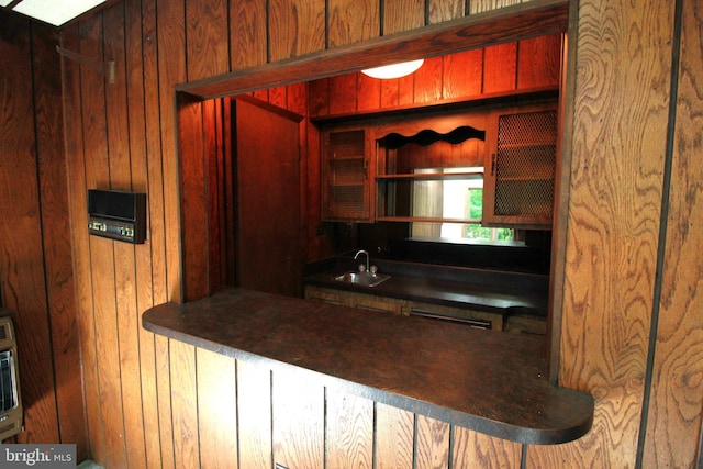 kitchen featuring wood walls, a sink, and dark countertops