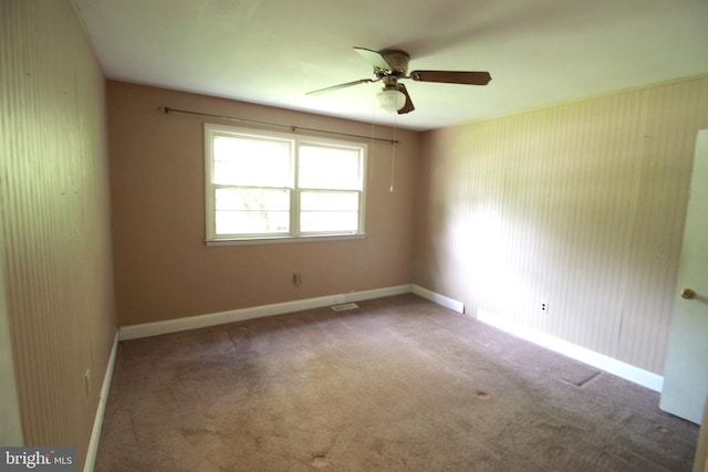 carpeted spare room with ceiling fan and baseboards