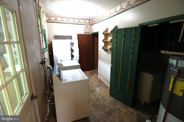 laundry area with stone finish flooring, gas water heater, and washing machine and clothes dryer