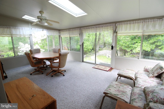 sunroom with a skylight, healthy amount of natural light, carpet flooring, and vaulted ceiling