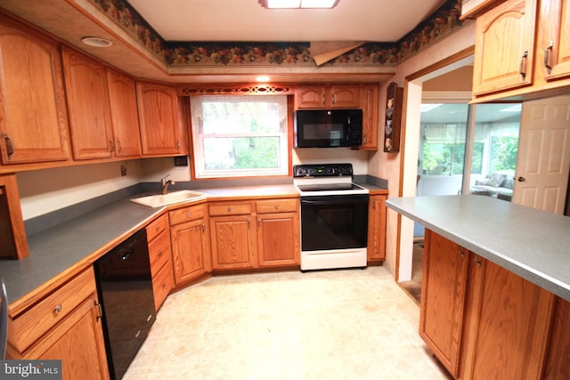 kitchen with black appliances, a sink, light flooring, and brown cabinetry