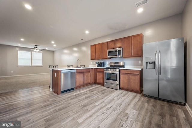 45 Quigley Ct, Camden Wyoming, DE 19934 - kitchen with appliances with stainless steel finishes, open floor plan, light countertops, light wood-style floors, and brown cabinetry