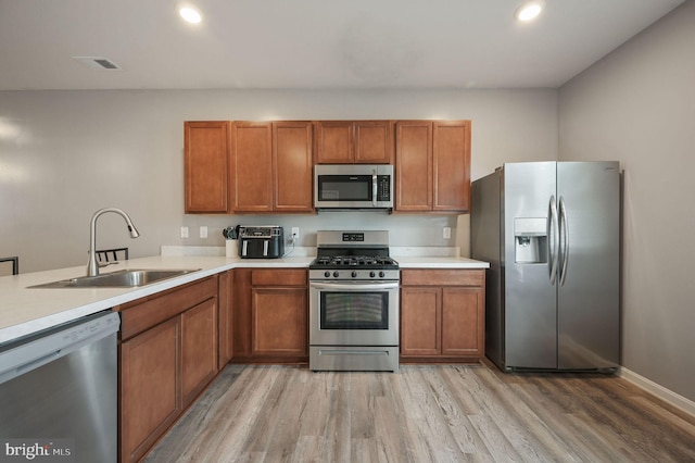 45 Quigley Ct, Camden Wyoming, DE 19934 - kitchen featuring stainless steel appliances, a sink, light wood finished floors, brown cabinets, and light countertops