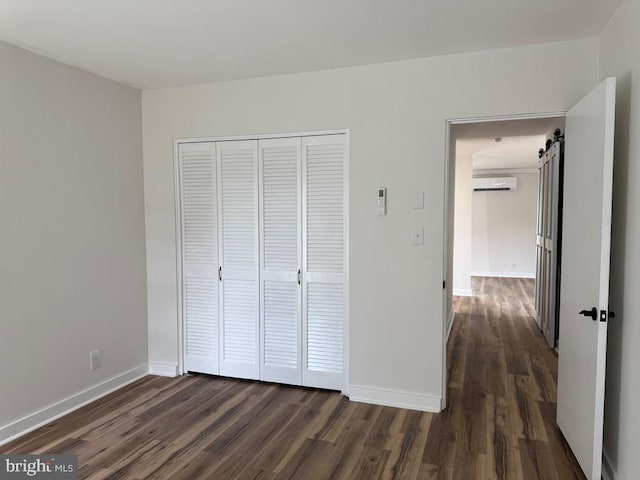 195 S Dr Unit E6, Kilmarnock, VA 22482 - unfurnished bedroom featuring a wall unit AC, dark wood-type flooring, a closet, and baseboards