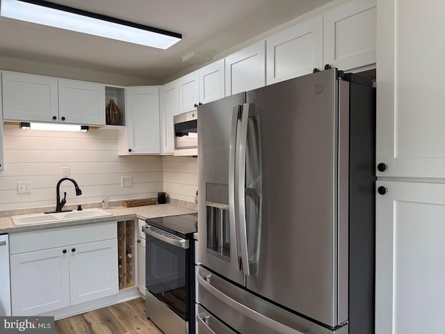 195 S Dr Unit E6, Kilmarnock, VA 22482 - kitchen with stainless steel appliances, a sink, white cabinets, light countertops, and light wood-type flooring