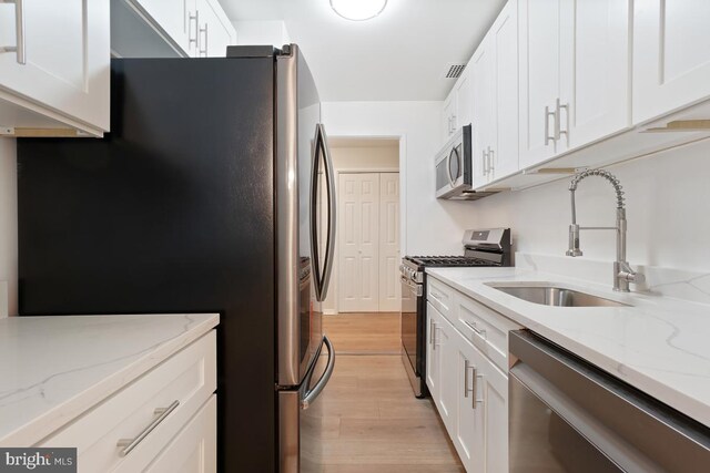 1900 Lyttonsville Rd Unit 216, Silver Spring, MD 20910 - kitchen with stainless steel appliances, a sink, light wood-style floors, and white cabinetry