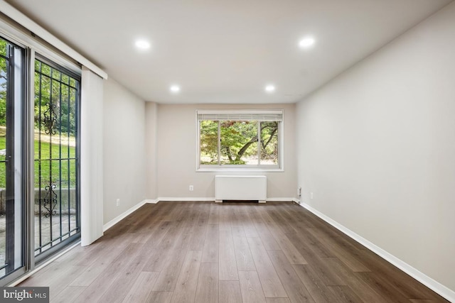 1900 Lyttonsville Rd Unit 216, Silver Spring, MD 20910 - empty room featuring radiator heating unit, healthy amount of natural light, wood finished floors, baseboards, and recessed lighting