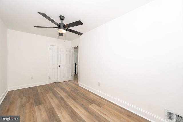 unfurnished bedroom featuring baseboards, wood finished floors, a closet, and a ceiling fan