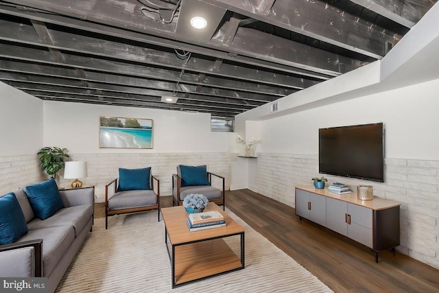 living room with wood finished floors, wainscoting, and brick wall